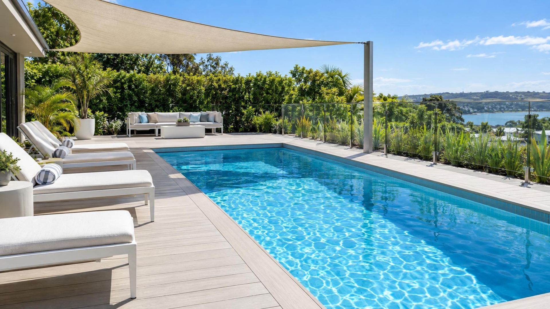 A composite pool deck with glass railing and lounge chairs